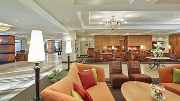 Un hall de hotel con recepción, zona de estar y área de comedor.