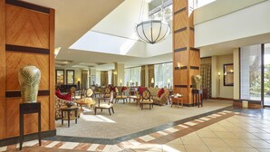 Eine geräumige Lobby mit hoher Decke, großen Fenstern und einem zentralen Kronleuchter.