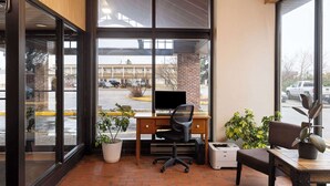 Un espace d’accueil avec un bureau, un ordinateur et des plantes en pot.