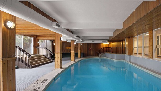 Une piscine intérieure avec des murs en bois et un escalier menant à un niveau supérieur.