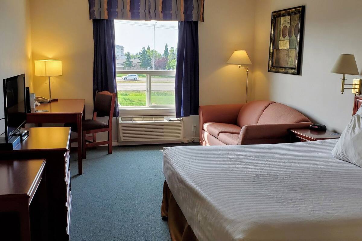 Habitación de hotel con cama, escritorio, silla y vistas al exterior.