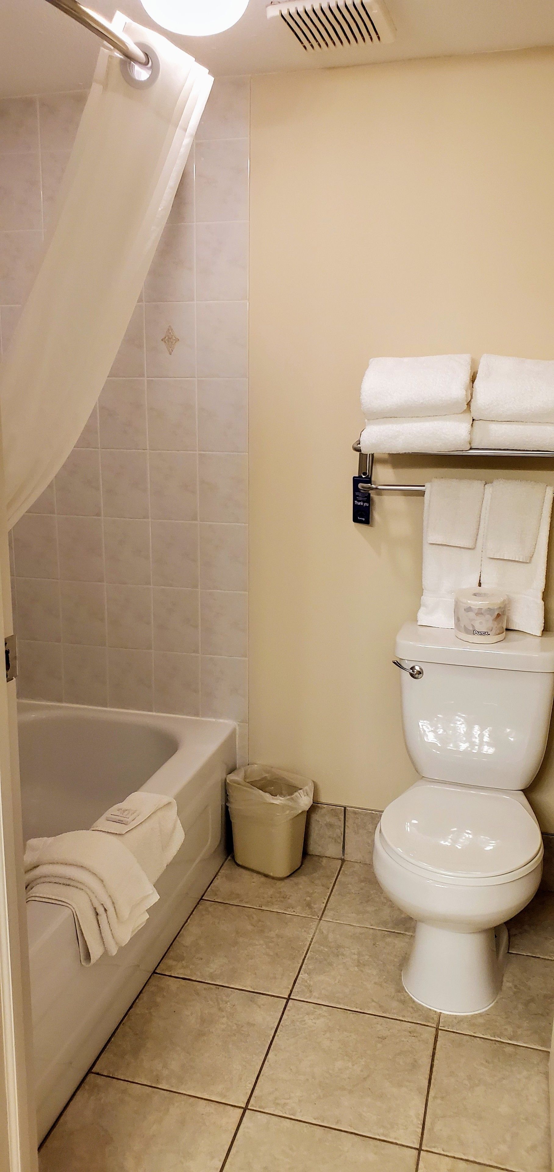 A bathroom with a bathtub, toilet, and a towel rack.