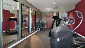 Un gimnasio con cintas de correr, una bicicleta estática y un muro de espejos.