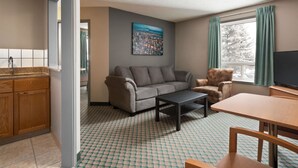 A living room with a sofa, armchair, coffee table, and TV.