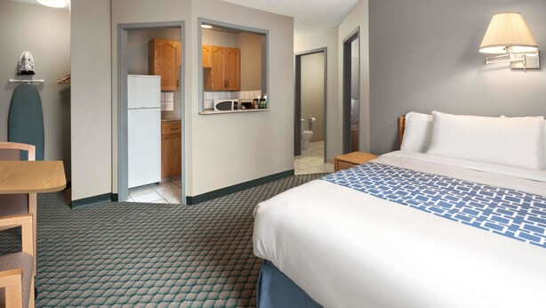 A hotel room with a bed, a desk, a chair, a microwave, and a small kitchenette.