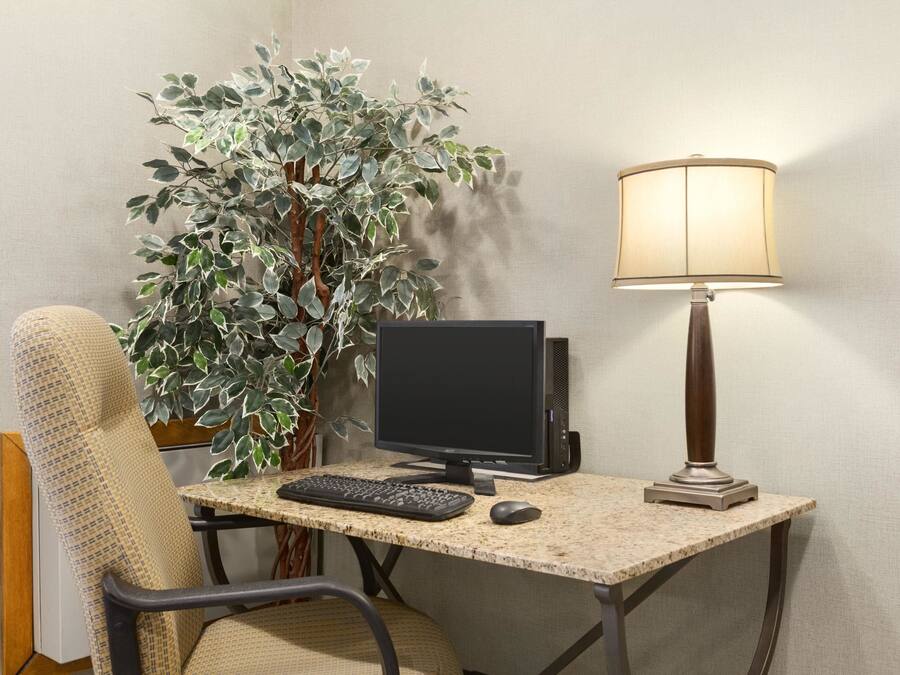 A workspace with a computer, keyboard, mouse, and a lamp on a table.