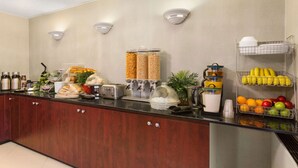 A kitchen with a coffee station, a fruit basket, and a bread display. - Travelodge by Wyndham Owen Sound (Owen Sound)