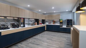 A modern kitchen with wooden cabinets, a marble backsplash, and a built-in coffee machine. - TownePlace Suites by Marriott Baton Rouge South (Baton Rouge)