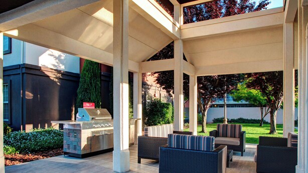 Un patio al aire libre con una parrilla, muebles de mimbre y vistas del paisaje circundante.