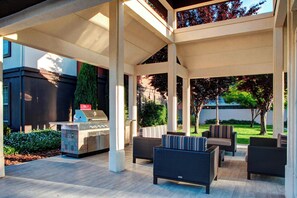 An outdoor patio area with a grill, wicker furniture, and a view of the surrounding landscape.