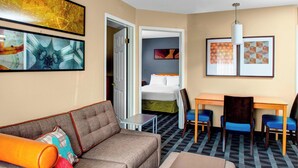 Habitación de hotel con sofá, una mesita, cama y escritorio con sillas.
