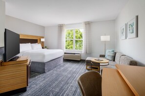 A hotel room with a bed, a desk, a chair, a TV, a lamp, and a window with curtains. - TownePlace Suites by Marriott Manchester (Manchester)