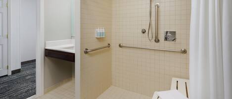 Un bagno accessibile ai disabili con doccia, maniglioni e lavandino bianco.