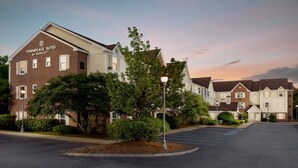 A townhouse complex with a brick facade, a landscaped front yard, and a parking lot. - TownePlace Suites by Marriott Manchester (Manchester)