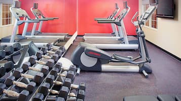 Uma academia com esteiras, aparelhos de musculação e halteres.