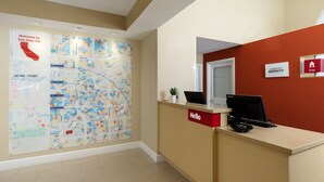 Zona de recepción de un hotel con un mapa grande en la pared, un mostrador de recepción y un cartel que indica el hotel Marriott Bonvoy.