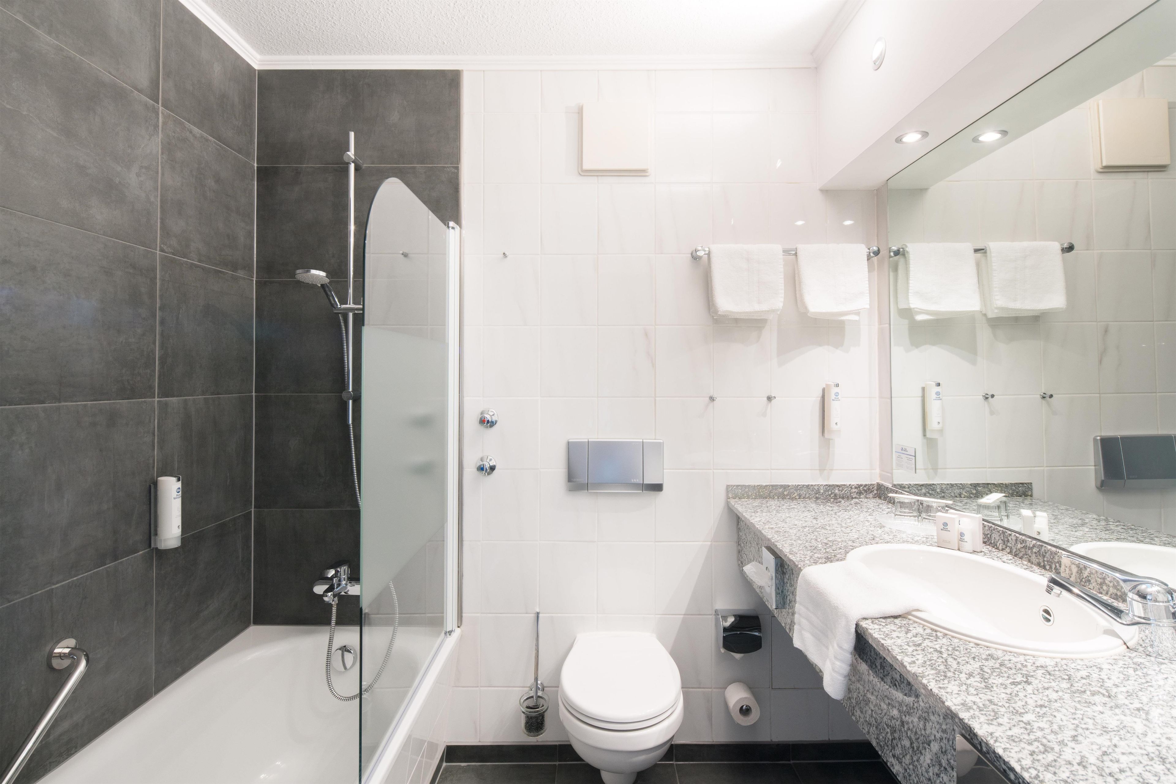 A modern bathroom with a shower, toilet, and sink.