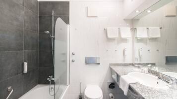 A modern bathroom with a shower, toilet, and sink.