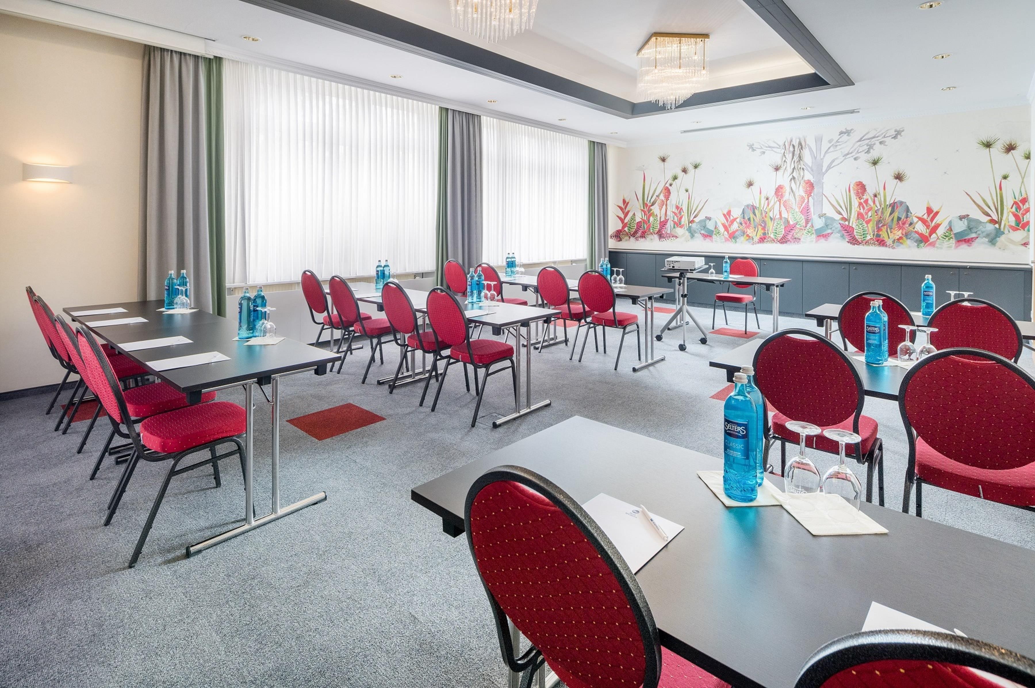 A conference room with tables, chairs, water bottles, and a decorative wall mural.