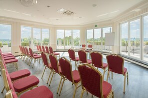 A conference room with rows of red chairs, a table, and large windows offering a view of the landscape. - Best Western Hotel Am Papenberg (Goettingen)