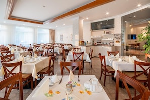 A hotel dining area with multiple tables set for guests, a bar area, and a television screen. - Best Western Hotel Am Papenberg (Goettingen)