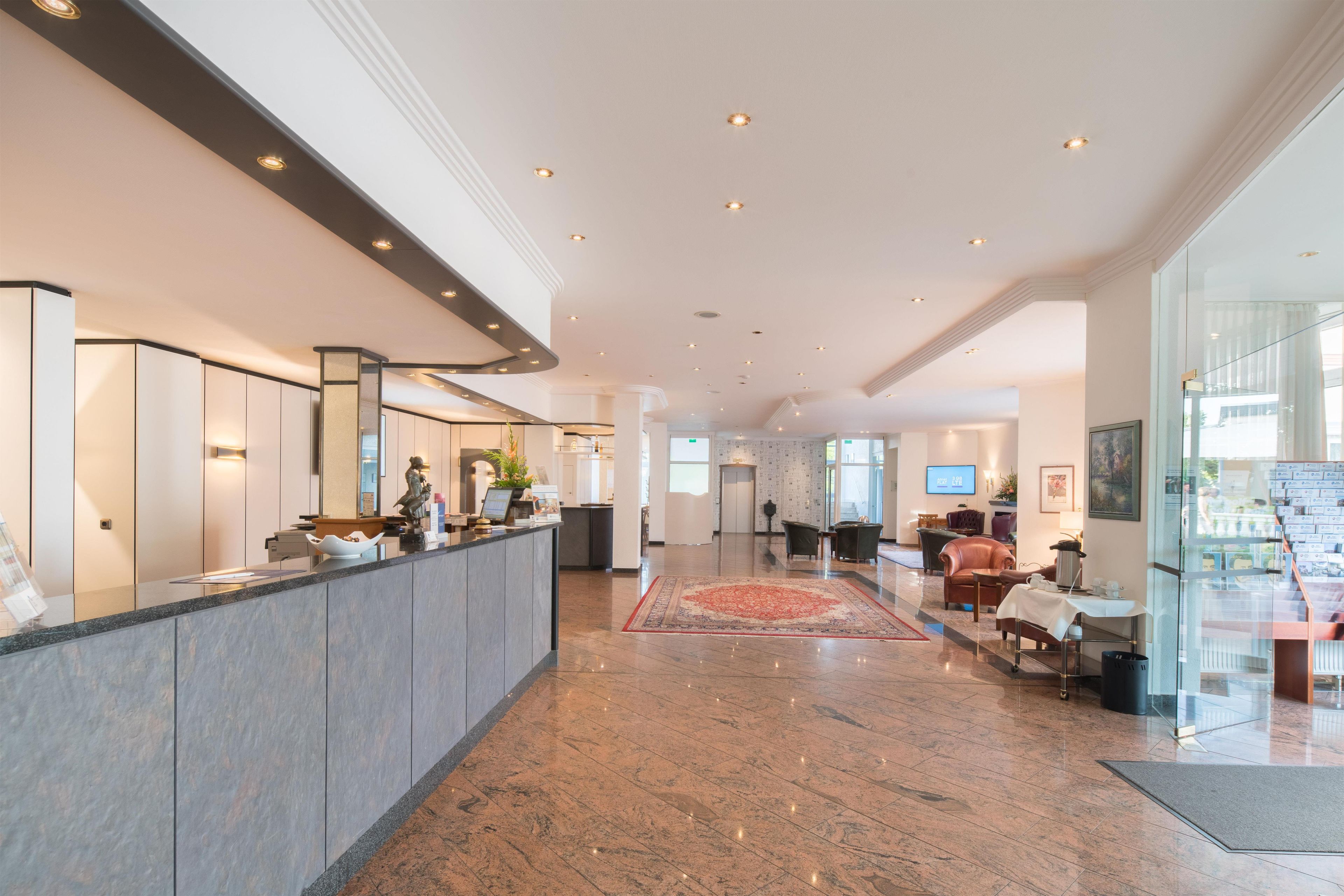 Eine Hotelhalle mit Rezeption, Sitzgelegenheiten und einem großen Fenster.