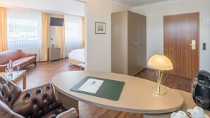 Une chambre d’hôtel comprenant un lit, un canapé, un bureau avec une lampe, une machine à café et un téléviseur.