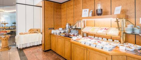 Zona de bufé con diferentes estaciones de comida, que incluye una estación de café y una selección de quesos.