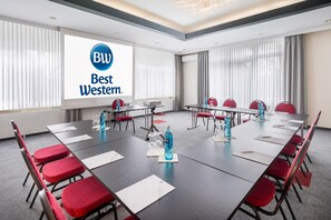 A conference room with a large screen displaying 'BW Best Western' logo, multiple tables with chairs, and water bottles on the tables. - Best Western Hotel Am Papenberg (Goettingen)