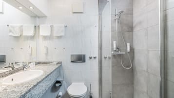 Ein modernes Badezimmer mit einer gläsernen Dusche, einem мраморном Waschbecken und einer Toilette.