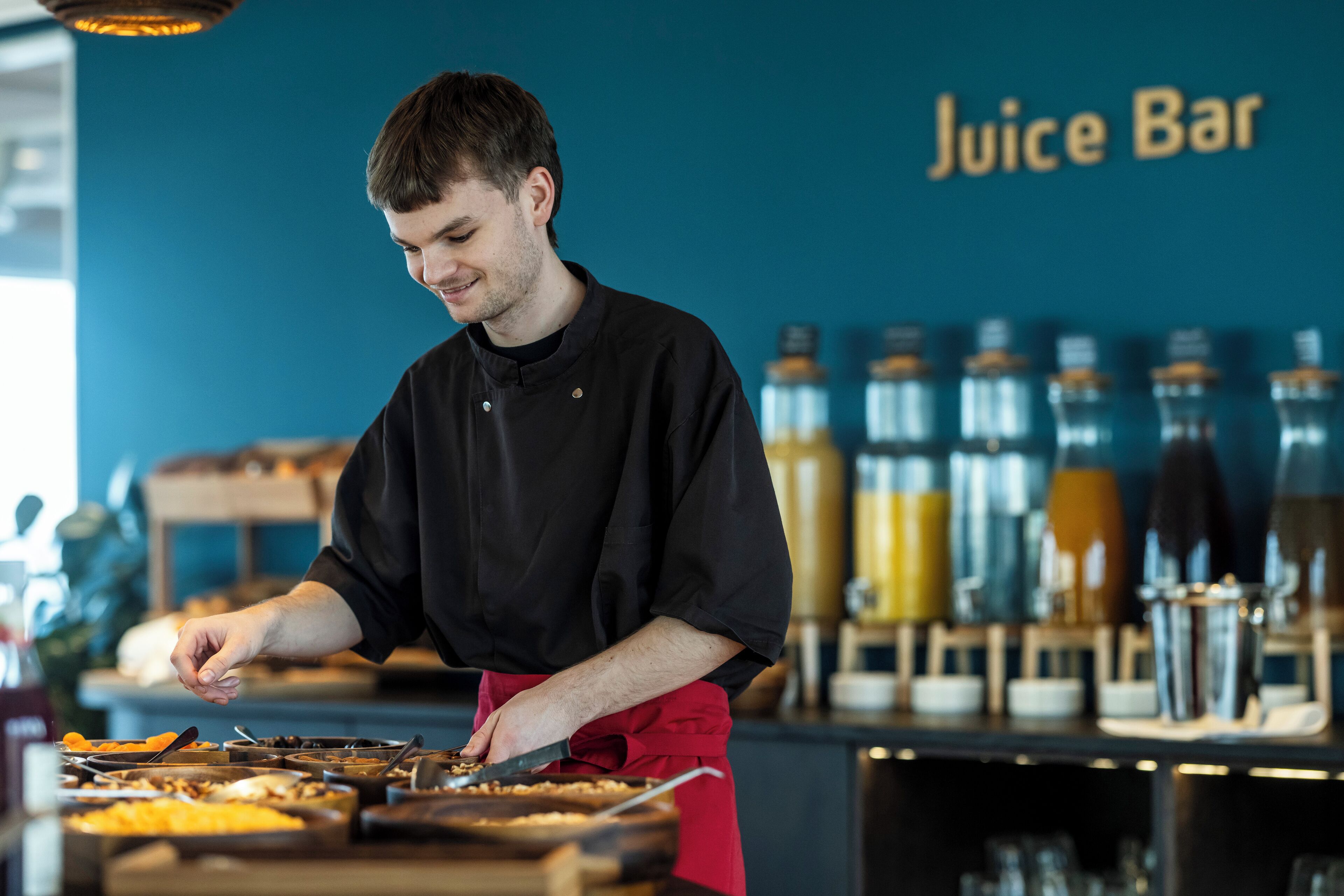 A person preparing food at a counter with a 'Juice Bar' sign in the background.