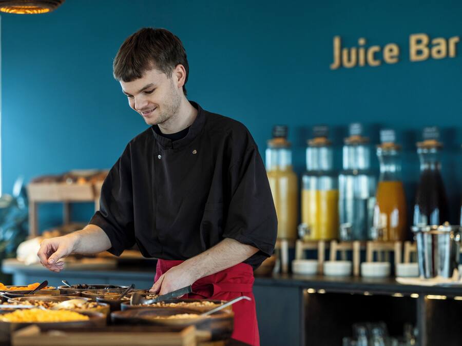 A person preparing food at a counter with a 'Juice Bar' sign in the background.