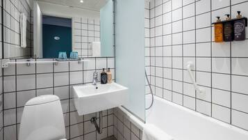 A modern bathroom with a white sink, toilet, and bathtub. There is a mirror above the sink and a towel hanging on the wall.