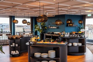 En moderne morgenmadsbar med et bredt udvalg af mad og udsigt over byen.