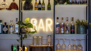 A bar area with shelves of liquor bottles, a neon 'BAR' sign, and a selection of glasses. - Hotel Atlantic (Aarhus)