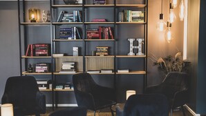 A modern library with bookshelves, black chairs, and a lamp. - Hotel Atlantic (Aarhus)