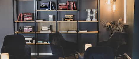 Une bibliothèque moderne avec des étagères, des chaises noires et une lampe.