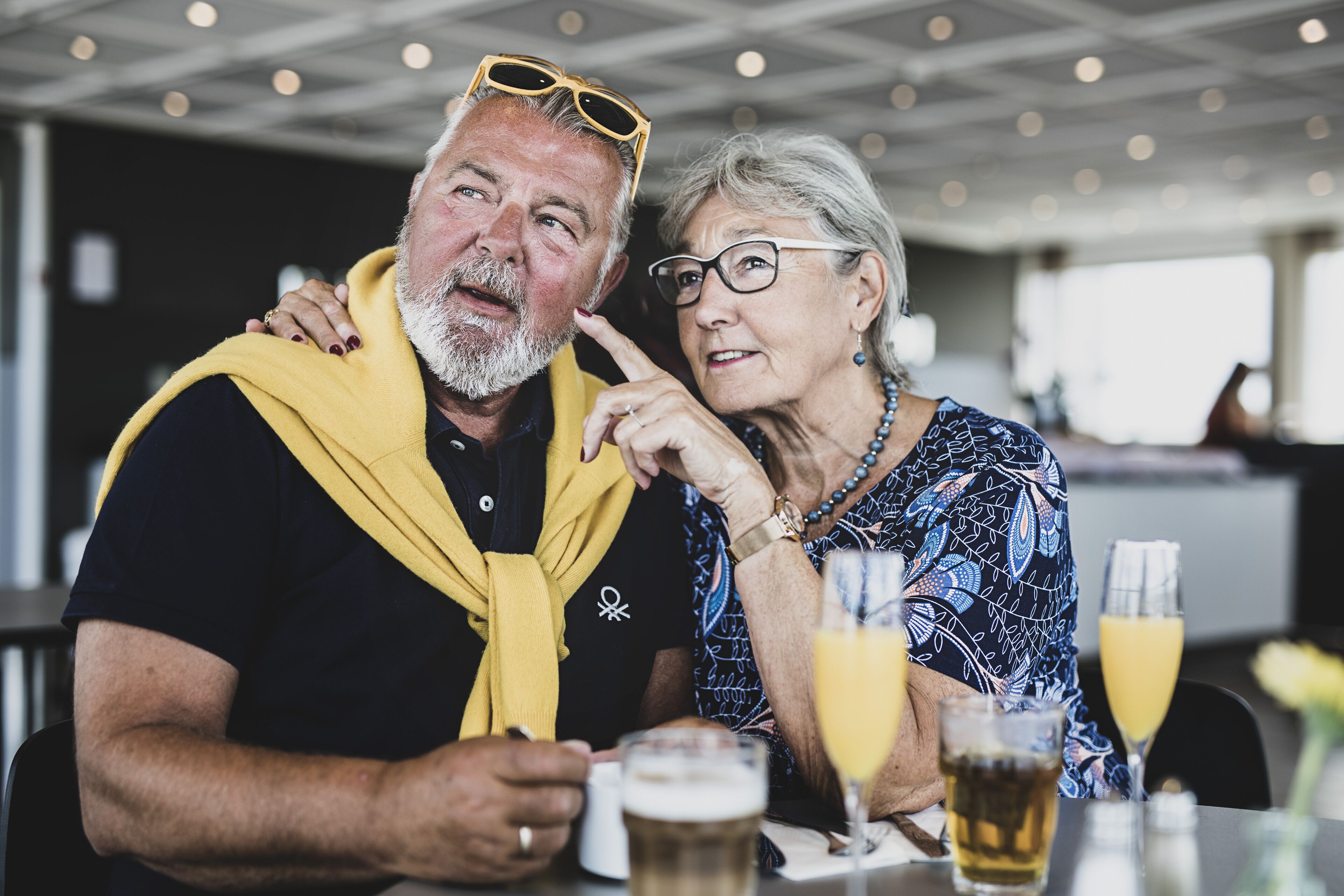 Un hombre y una mujer sentados a una mesa con bebidas, en un restaurante con una decoración moderna.