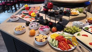Un bufé con diversos alimentos, como frutas, verduras, quesos y carnes.