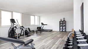 Un gimnasio moderno con máquinas de cardio, bancos de pesas y una variedad de equipamiento para ejercitarse.