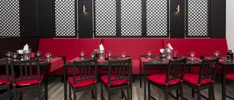 A restaurant with red cushioned seating, black tables, and a wooden floor.