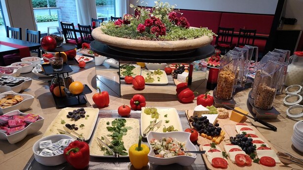 Una mesa de buffet con diversos alimentos y un arreglo floral central.