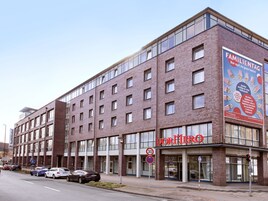 Un edificio de varios pisos con un llamativo letrero que dice 'DormMerc', indicando un hostal o dormitorio.