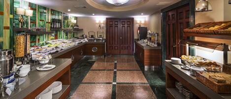 A hotel breakfast area with buffet counters, a central door, and a tiled floor.