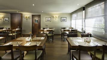 A restaurant with multiple dining tables, chairs, and a large window providing natural light.
