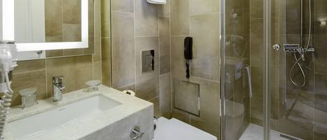 A modern bathroom with a glass-enclosed shower, a white sink, and a large mirror.