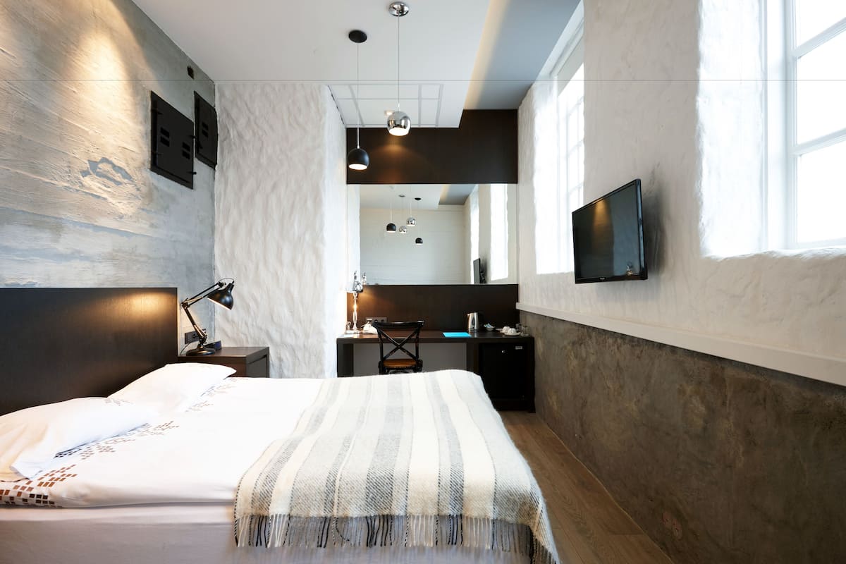 Ein modernes Schlafzimmer mit Bett, Schreibtisch und Fernseher.