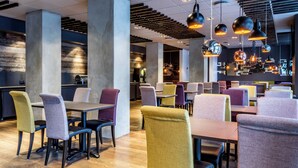Interior moderno de restaurante con techos altos, vigas a la vista y luminarias contemporáneas.