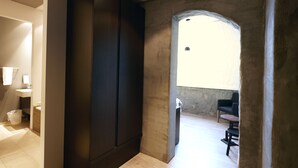 Un interior moderno con un armario oscuro, un lavamanos pequeño y vistas a una zona de estar a través de un arco.