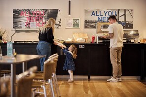 A restaurant interior with a counter, seating area, and a menu stand. - CABINN Vejle Hotel (Vejle)